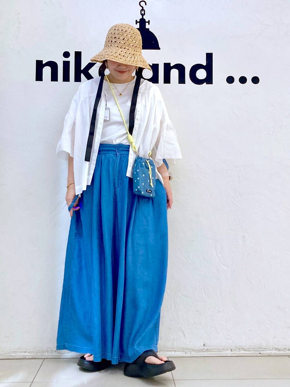 ブルー系のショルダーバッグ、ブラック系のサンダル、ブルー系のデニムパンツを着用したレディースの春コーディネートの2枚目の写真