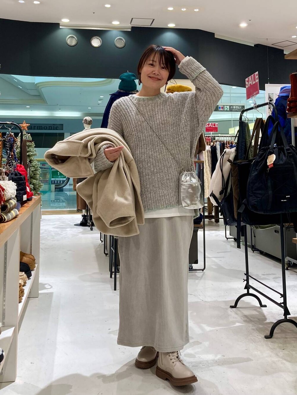 シルバー系のショルダーバッグ、ベージュ系のブーツ、ベージュ系のブルゾンを着用したレディースの冬コーディネートの2枚目の写真