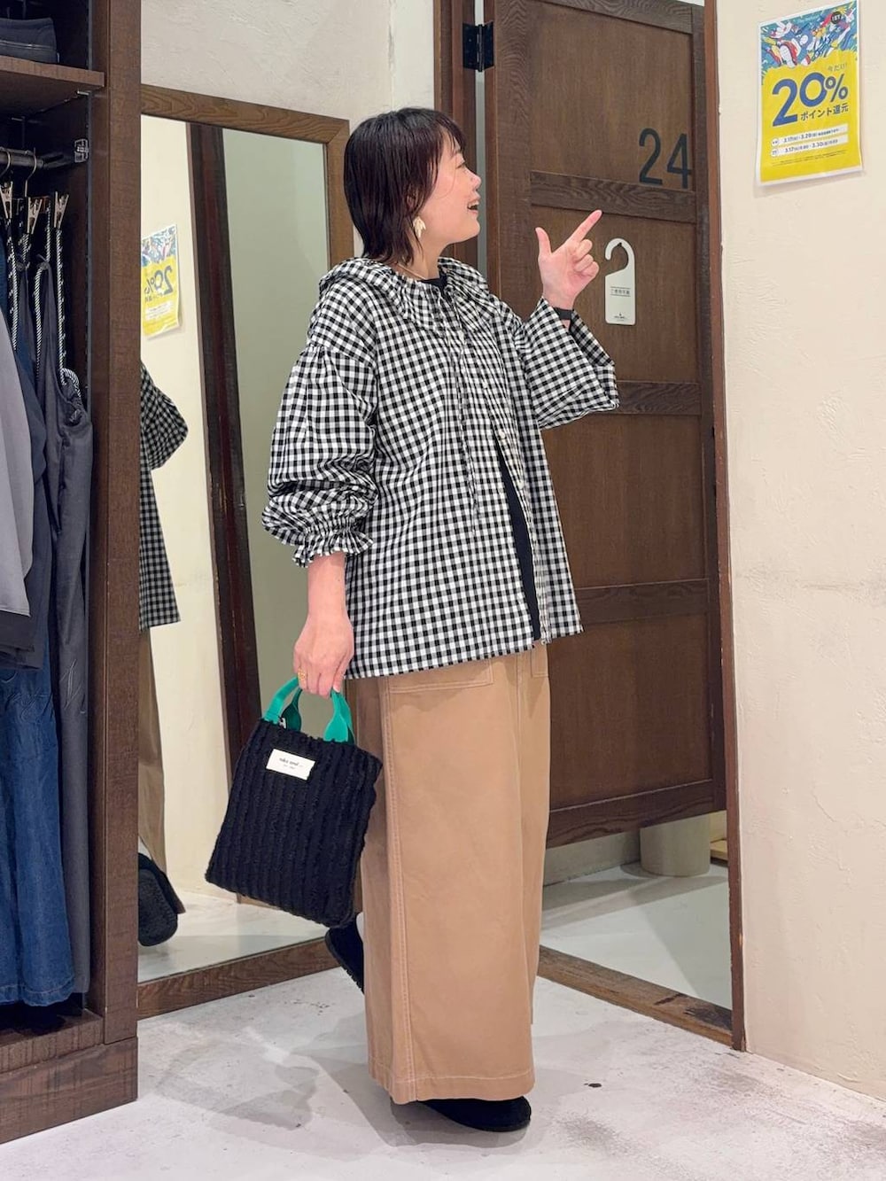 イエロー系のスカート、ブラック系のパンプス、ブラック系のトートバッグを着用したレディースの春コーディネートの2枚目の写真