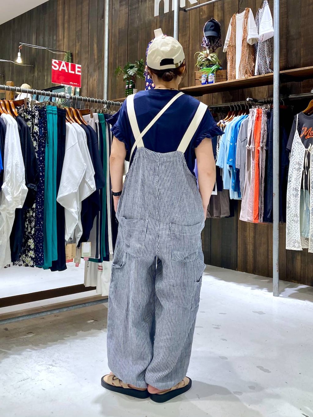 ブルー系のサロペット/オーバーオール、ブルー系のTシャツ/カットソー、ベージュ系のショルダーバッグを着用したレディースの夏コーディネートの4枚目の写真