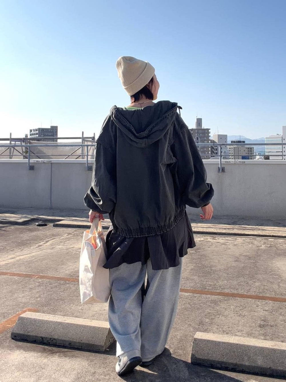 ホワイト系のトートバッグ、ブラック系のブルゾン、グレー系のワンピースを着用したレディースの冬コーディネートの3枚目の写真