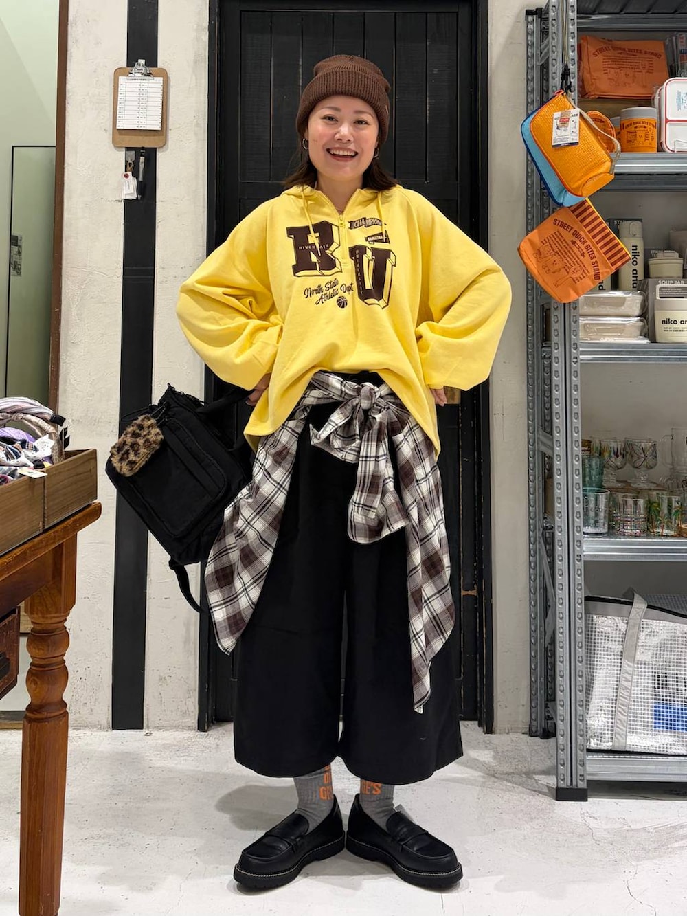 イエロー系のパーカー、ブラック系のその他パンツ、ブラック系のトートバッグを着用したレディースの秋コーディネートの2枚目の写真