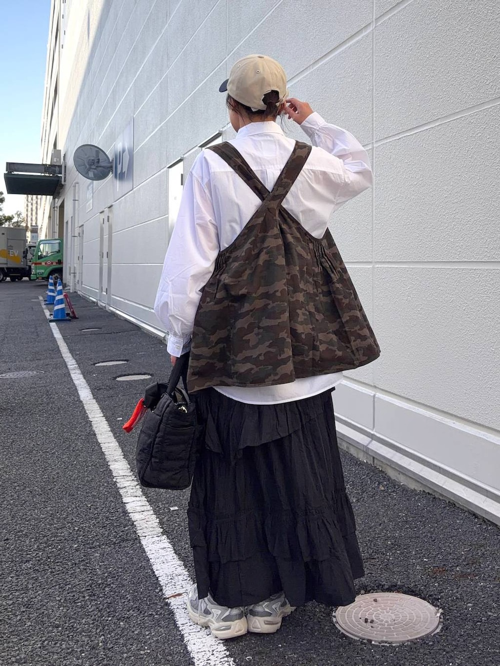 ブラック系のトートバッグ、ブラウン系のベスト、ホワイト系のシャツ/ブラウスを着用したレディースの春コーディネートの4枚目の写真