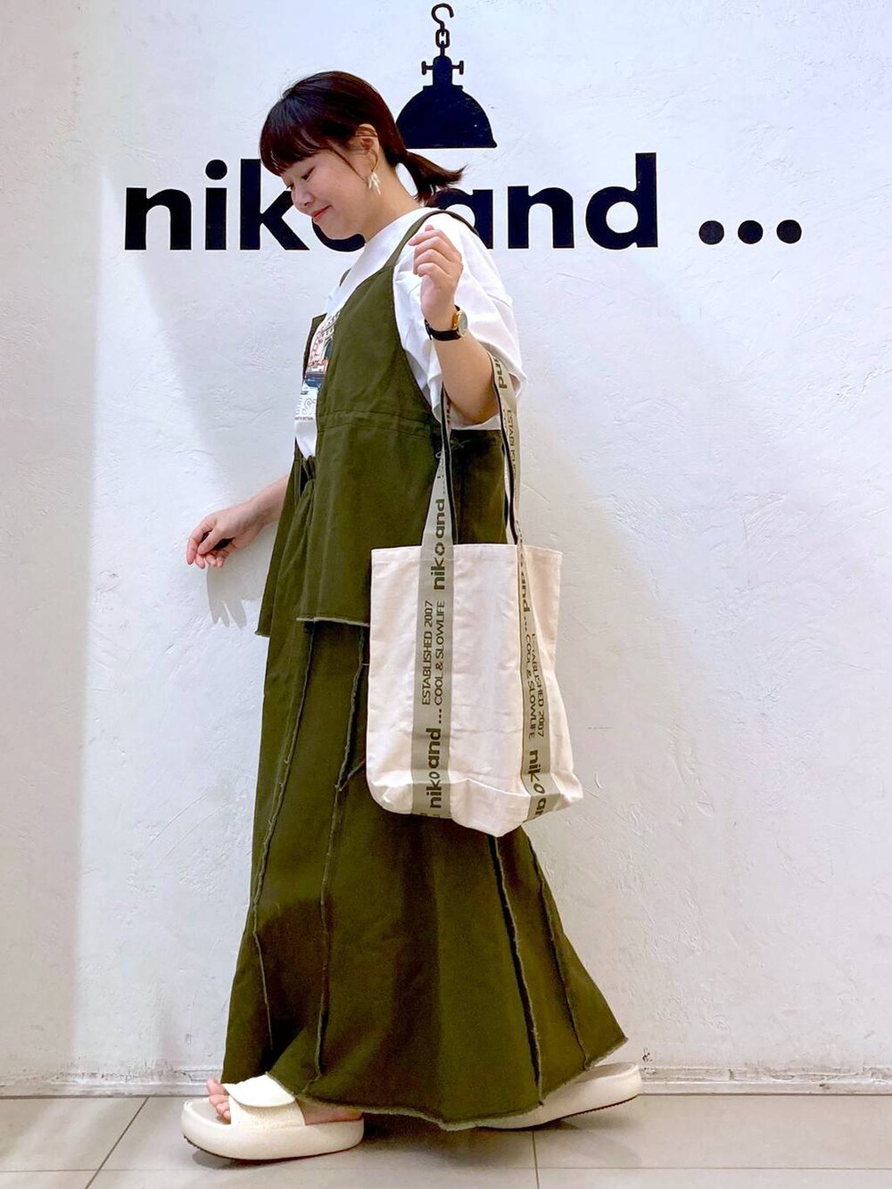 ベージュ系のトートバッグ、ベージュ系のサンダル、ホワイト系のTシャツ/カットソーを着用したレディースの春コーディネートの3枚目の写真