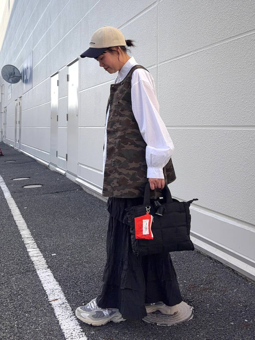 ブラック系のトートバッグ、ブラウン系のベスト、ホワイト系のシャツ/ブラウスを着用したレディースの春コーディネートの3枚目の写真