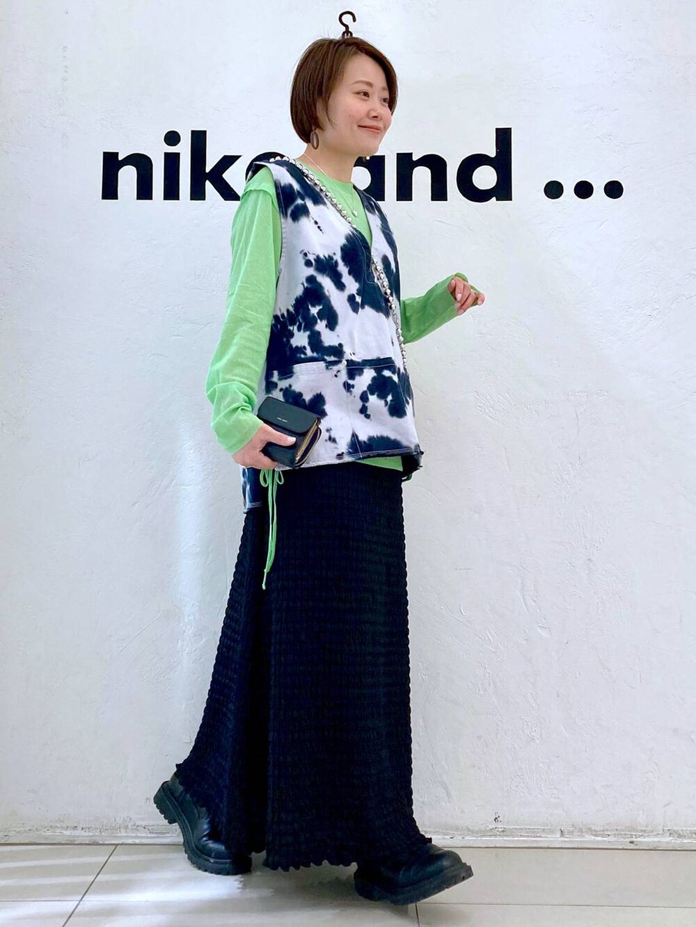 ブルー系のベスト、ブラック系のスカート、グリーン系のTシャツ/カットソーを着用したレディースの春コーディネートの3枚目の写真