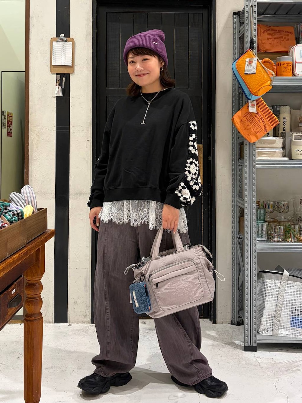 グレー系のトートバッグ、ブラック系のスウェット、パープル系のデニムパンツを着用したレディースの秋コーディネートの2枚目の写真