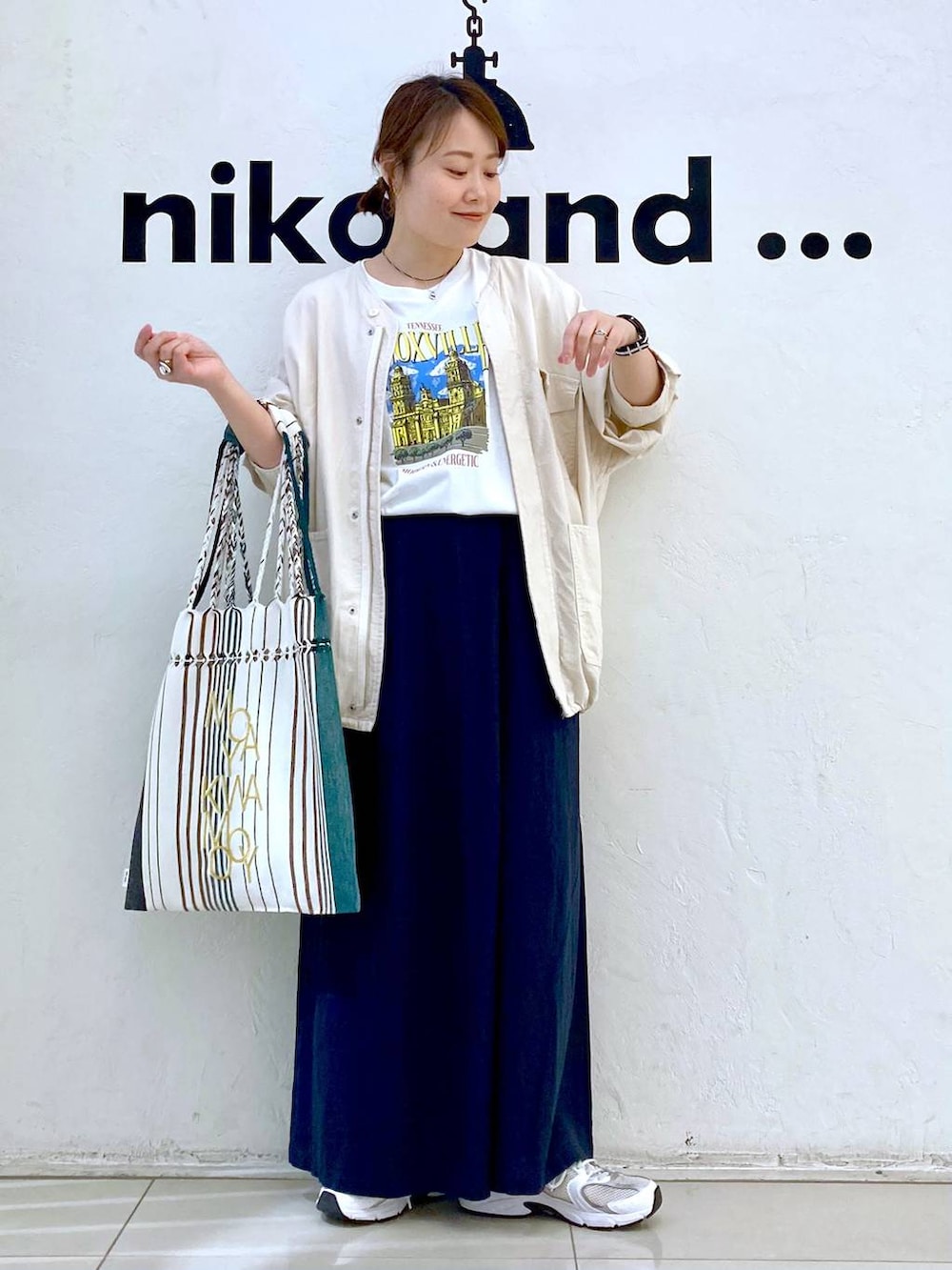 ホワイト系のTシャツ/カットソー、ブラック系のトートバッグ、ベージュ系のブルゾンを着用したレディースの春コーディネートの2枚目の写真