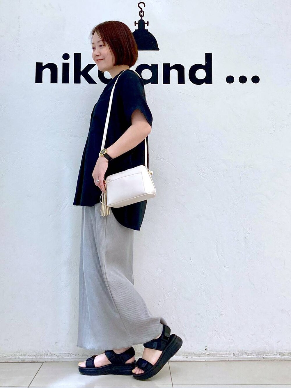 ブラック系のサンダル、ホワイト系のタンクトップ、ブラウン系のショルダーバッグを着用したレディースの夏コーディネートの5枚目の写真