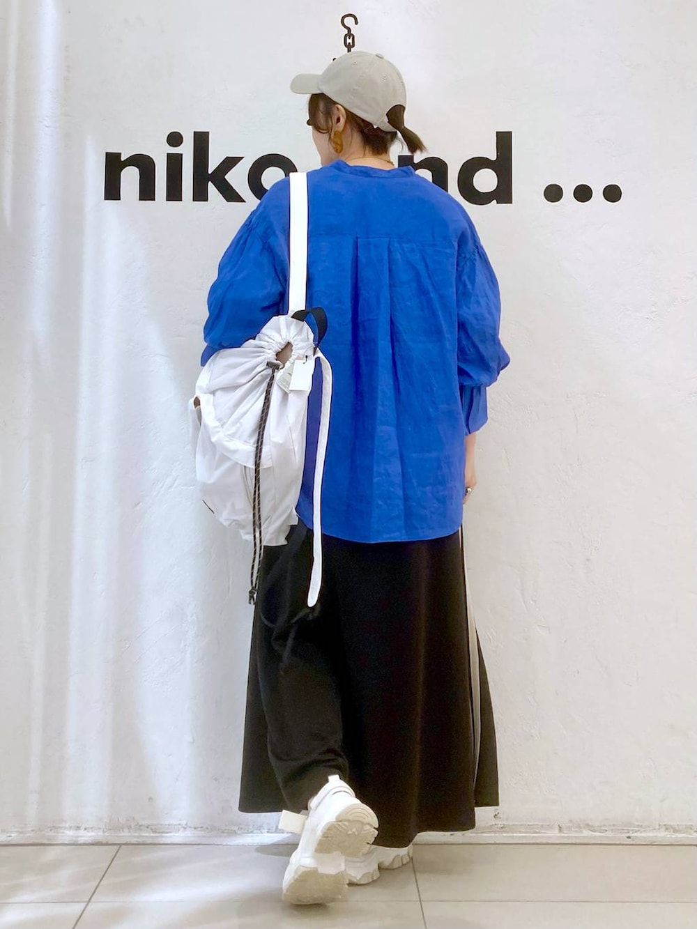 ベージュ系のバックパック/リュック、ホワイト系のTシャツ/カットソー、グレー系のスカートを着用したレディースの春コーディネートの4枚目の写真