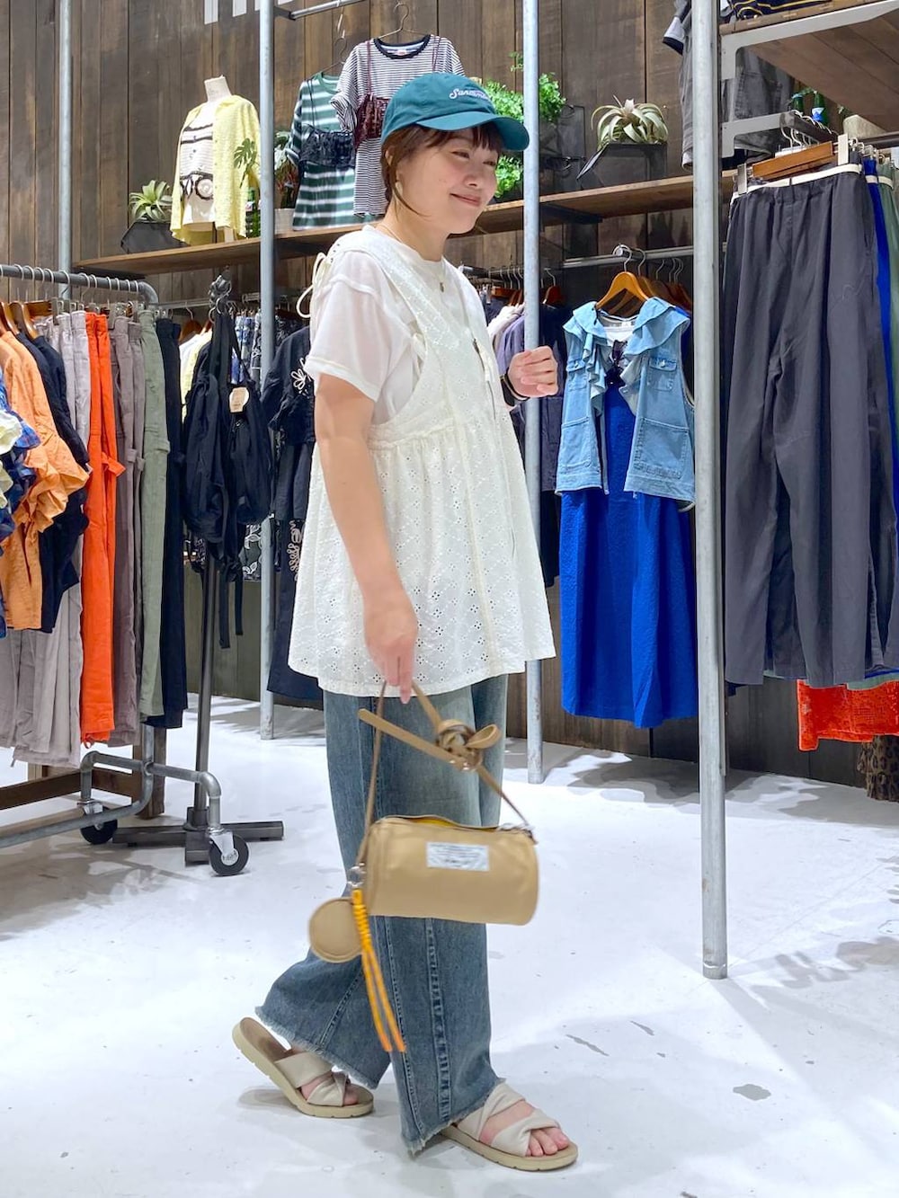 ブルー系のその他パンツ、ホワイト系のベスト、ベージュ系のショルダーバッグを着用したレディースの夏コーディネートの5枚目の写真