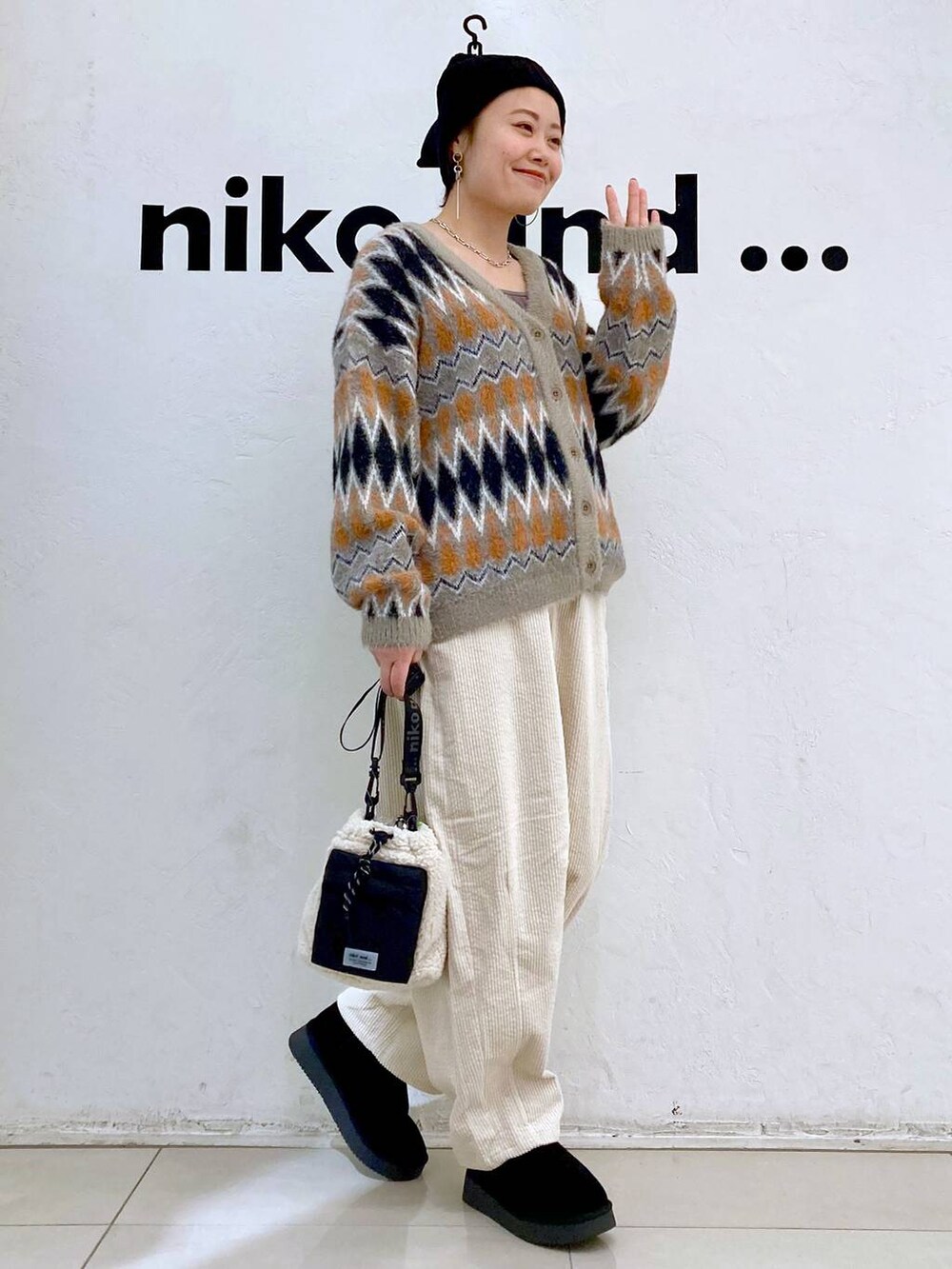 ブラウン系のカーディガン/ボレロ、ブラック系のブーツ、ベージュ系のショルダーバッグを着用したレディースの冬コーディネートの2枚目の写真