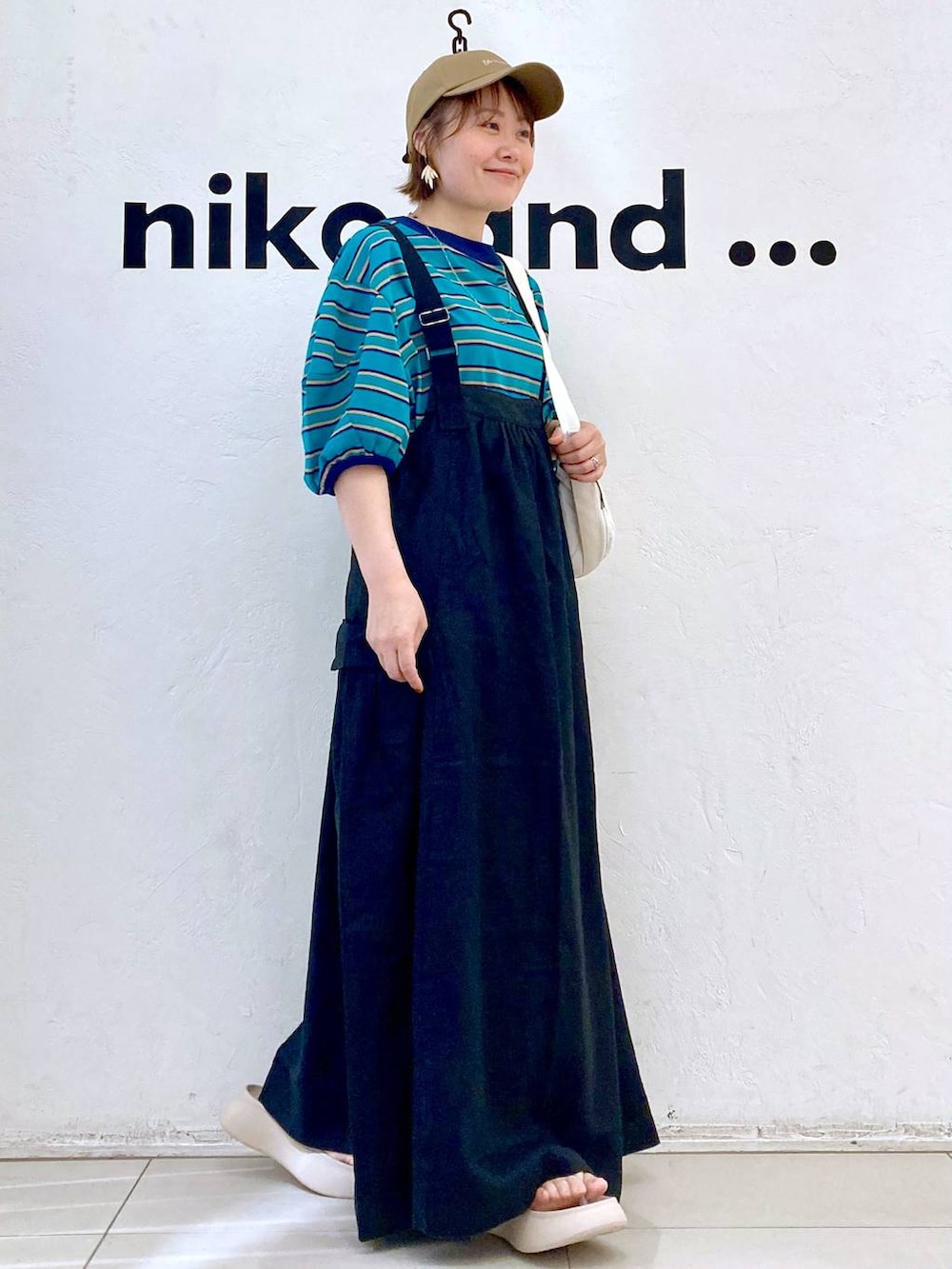 ベージュ系のサンダル、ホワイト系のショルダーバッグ、グリーン系のTシャツ/カットソーを着用したレディースの春コーディネートの5枚目の写真
