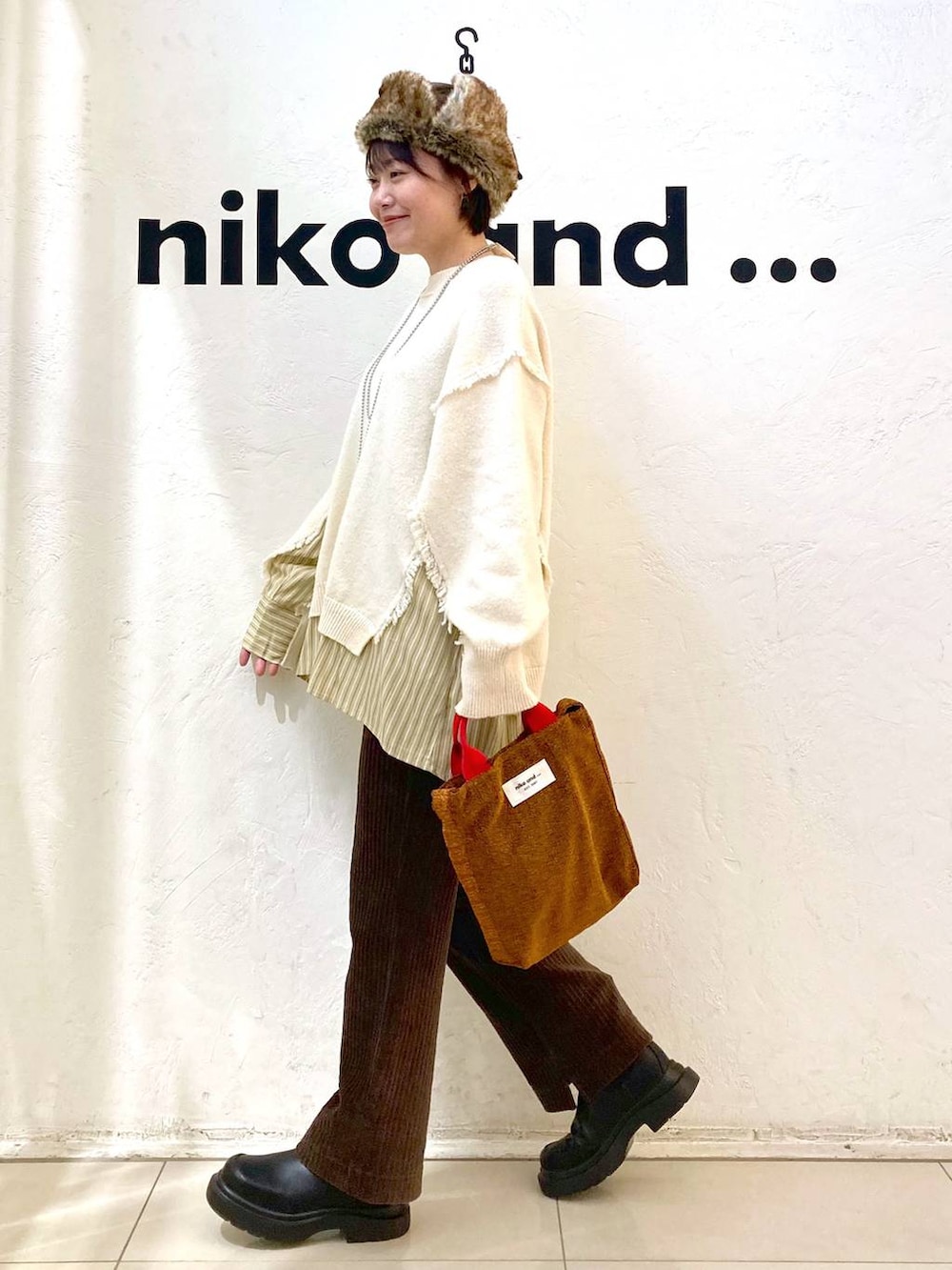 ブラウン系のその他パンツ、ブラック系のブーツ、レッド系のトートバッグを着用したレディースの冬コーディネートの4枚目の写真