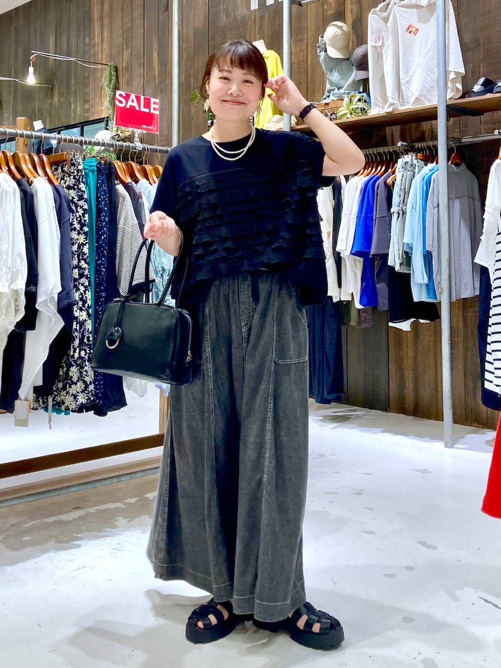 グレー系のスカート、ブラック系のボストンバッグ、ブラック系のTシャツ/カットソーを着用したレディースの夏コーディネートの2枚目の写真