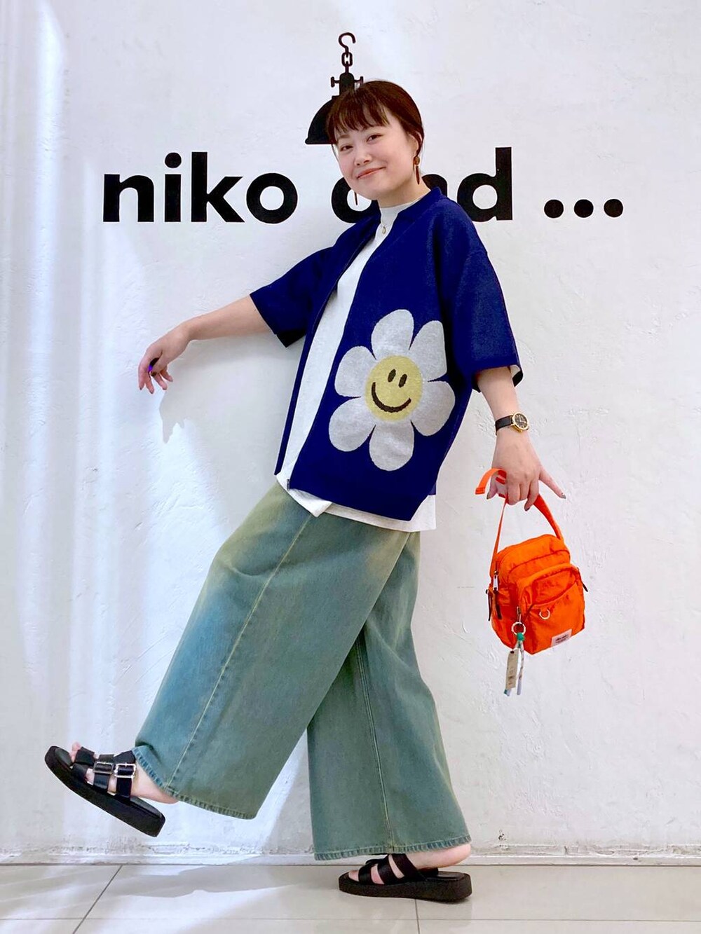 オレンジ系のショルダーバッグ、ベージュ系のTシャツ/カットソー、ブルー系のデニムパンツを着用したレディースの夏コーディネートの4枚目の写真