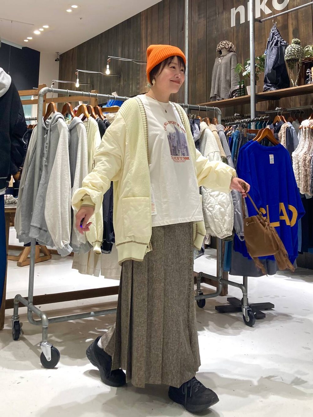 ブラウン系のスカート、ブラウン系のショルダーバッグ、ホワイト系のTシャツ/カットソーを着用したレディースの秋コーディネートの5枚目の写真