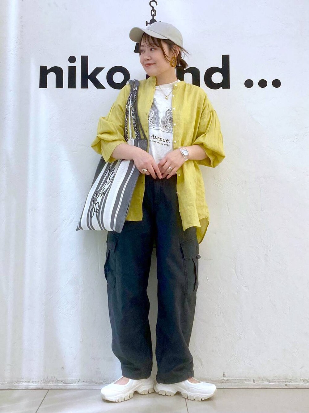 ベージュ系のTシャツ/カットソー、イエロー系のシャツ/ブラウス、グレー系のカーゴパンツを着用したレディースの春コーディネートの2枚目の写真