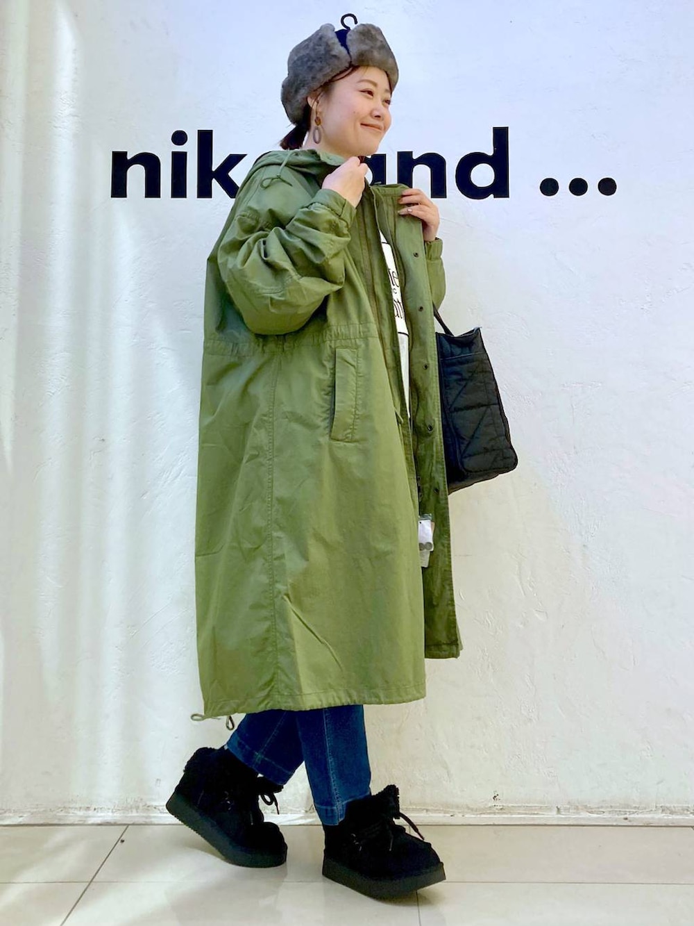 グリーン系のモッズコート、ブルー系のその他パンツ、ブラック系のトートバッグを着用したレディースの冬コーディネートの5枚目の写真