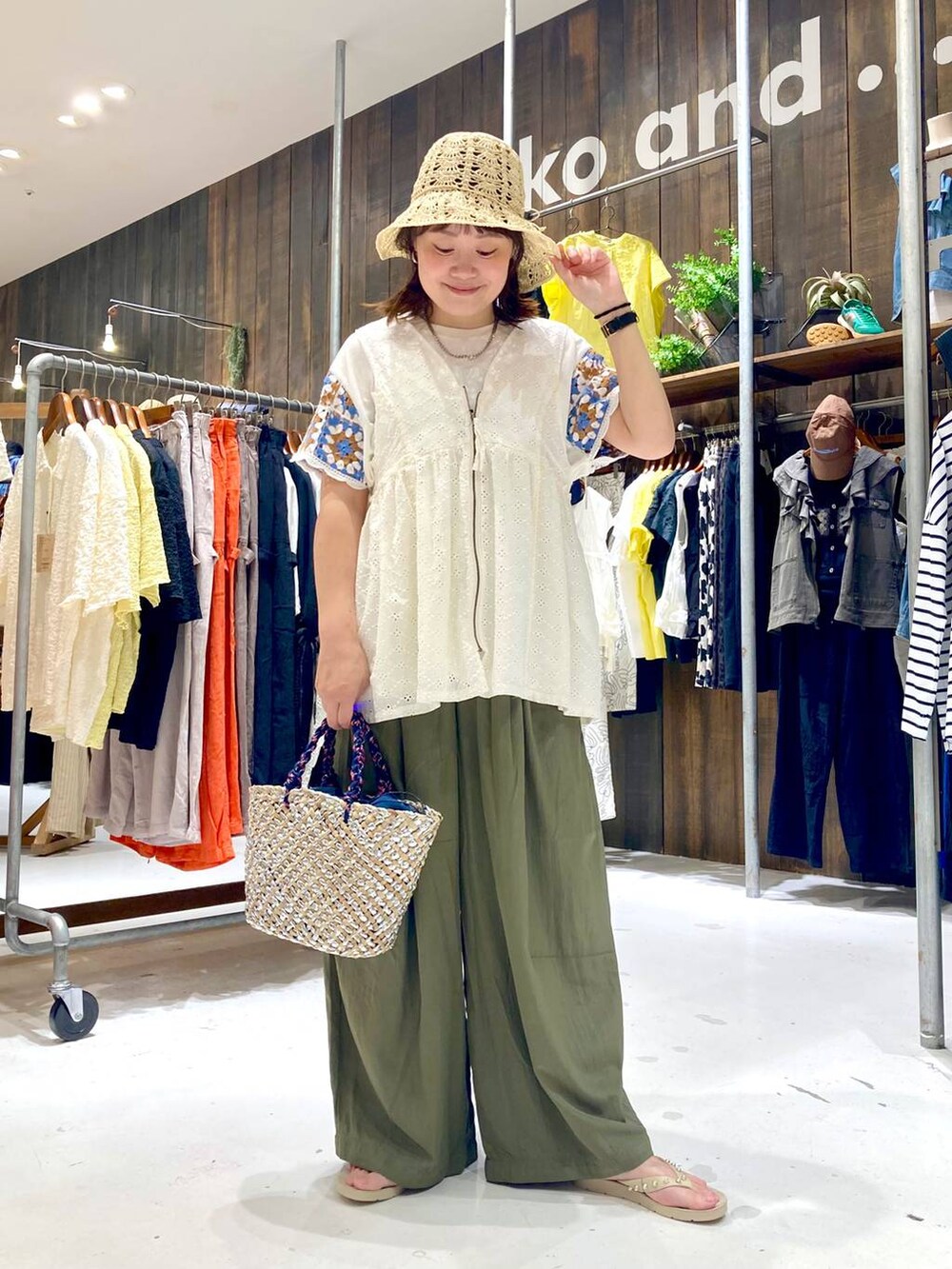 ホワイト系のベスト、ベージュ系のサンダル、グレー系のかごバッグを着用したレディースの夏コーディネートの2枚目の写真