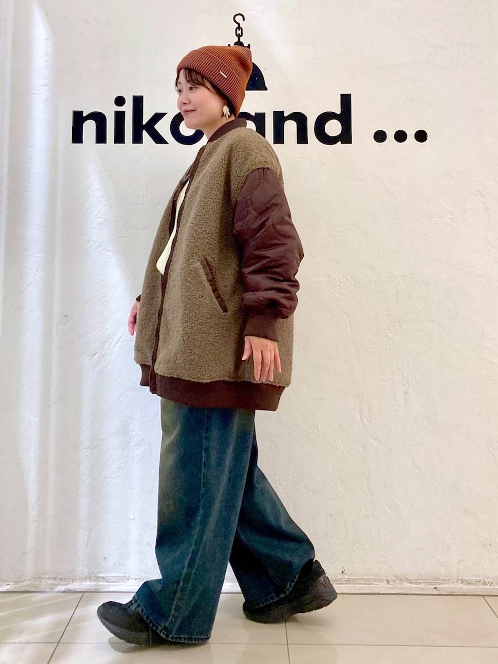 レッド系のMA-1、ベージュ系のニット/セーター、オレンジ系のニットキャップ/ビーニーを着用したレディースの秋コーディネートの4枚目の写真