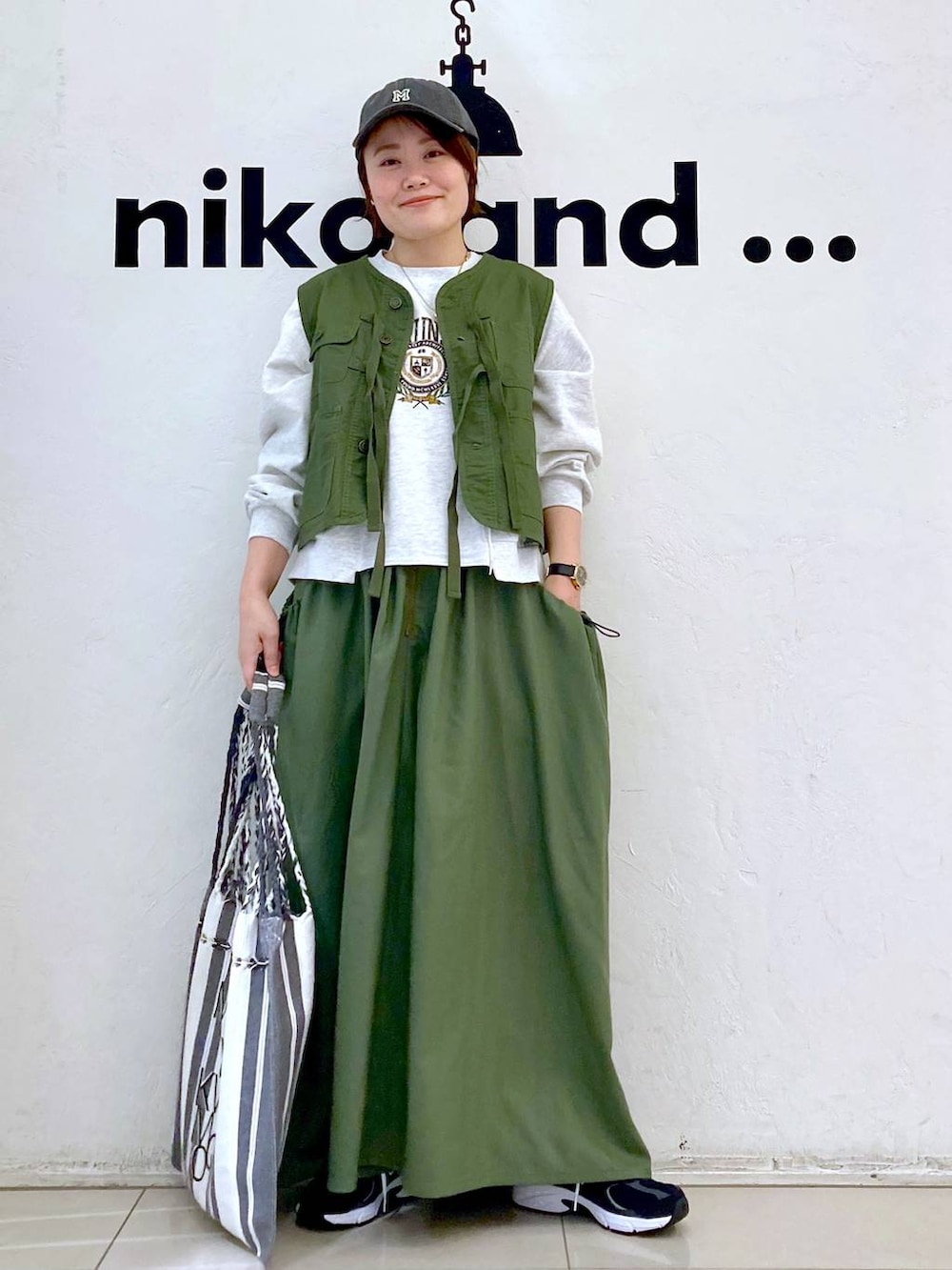 グリーン系のスカート、ベージュ系のTシャツ/カットソー、グリーン系のベストを着用したレディースの春コーディネートの2枚目の写真