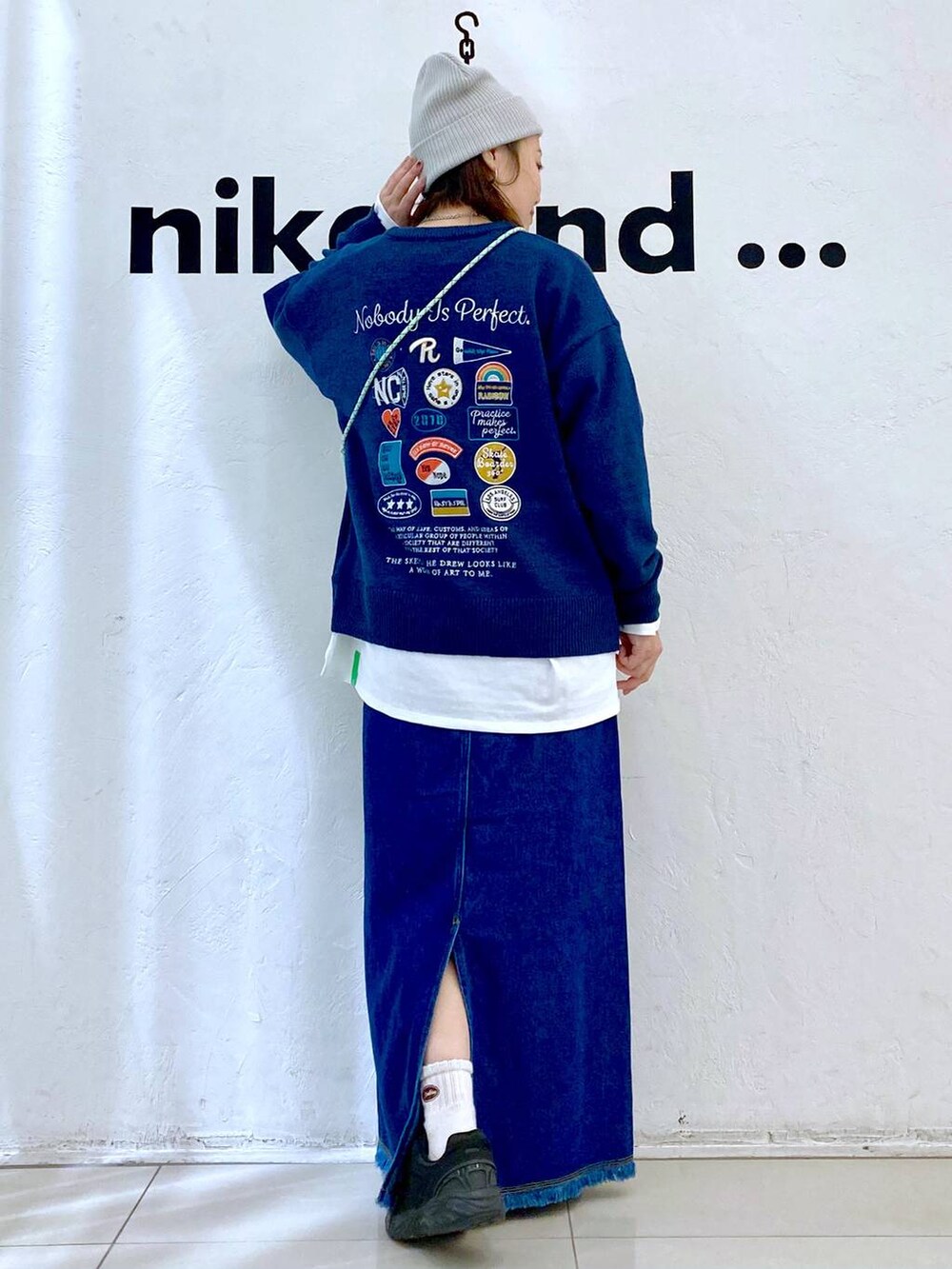 シルバー系のショルダーバッグ、ブルー系のデニムスカート、ブルー系のニット/セーターを着用したレディースの冬コーディネートの4枚目の写真