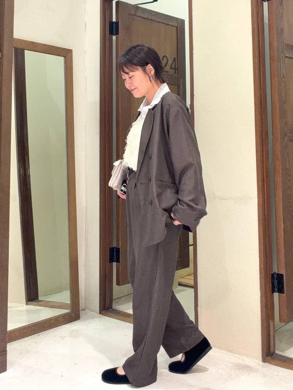 グレー系のショルダーバッグ、ブラック系のパンプス、ブラウン系のテーラードジャケットを着用したレディースの冬コーディネートの4枚目の写真