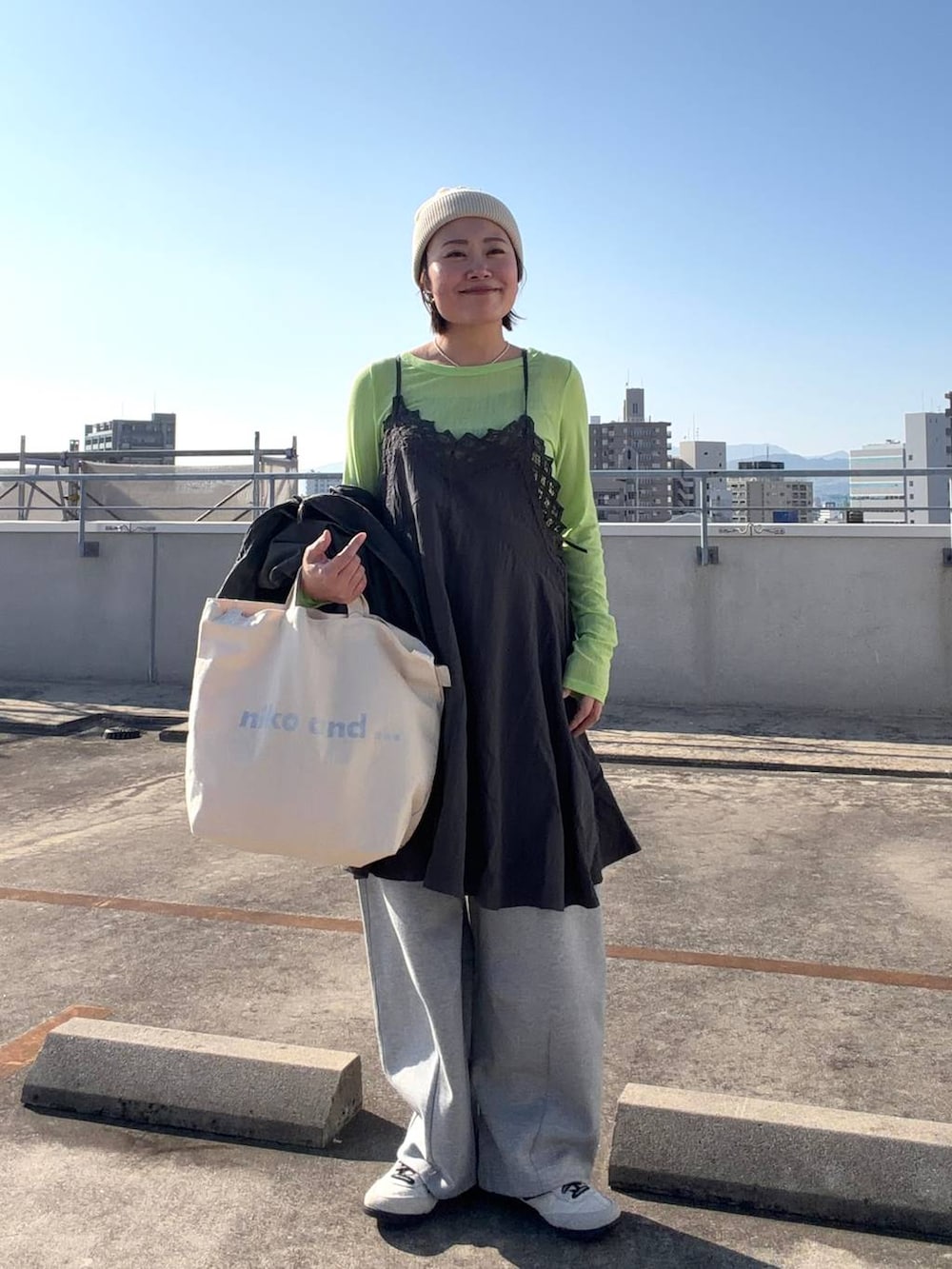 ホワイト系のトートバッグ、ブラック系のブルゾン、グレー系のワンピースを着用したレディースの冬コーディネートの5枚目の写真