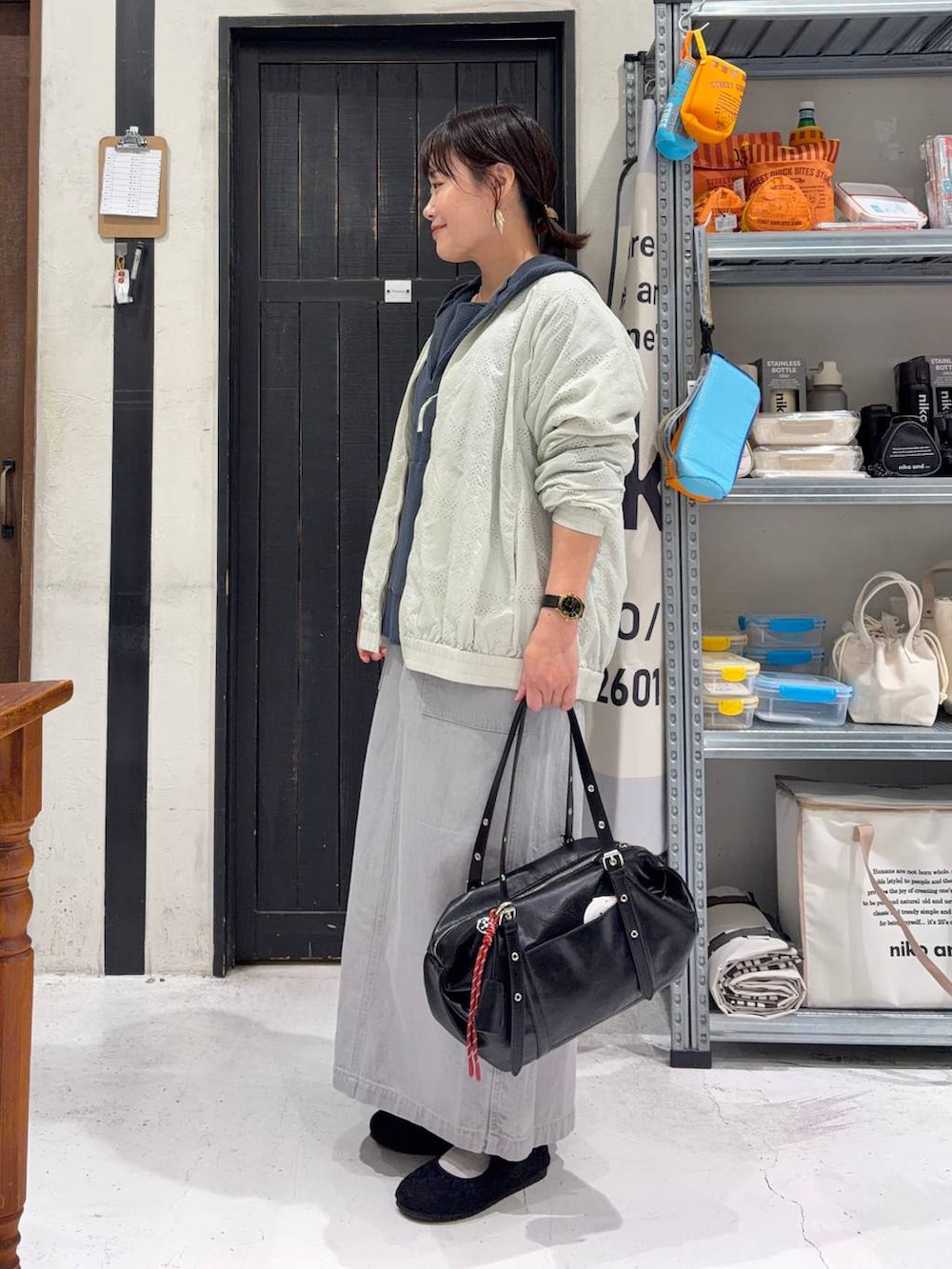 グレー系のスカート、ブラック系のパンプス、ホワイト系のブルゾンを着用したレディースの春コーディネートの3枚目の写真