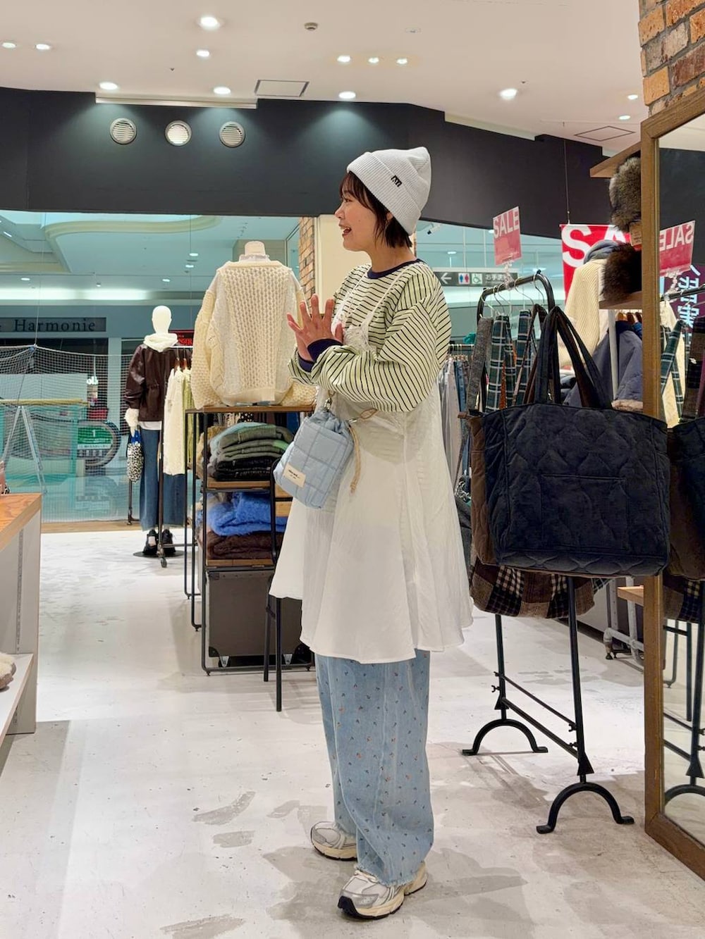 ホワイト系のスニーカー、ブルー系のショルダーバッグ、ブルー系のデニムパンツを着用したレディースの冬コーディネートの2枚目の写真