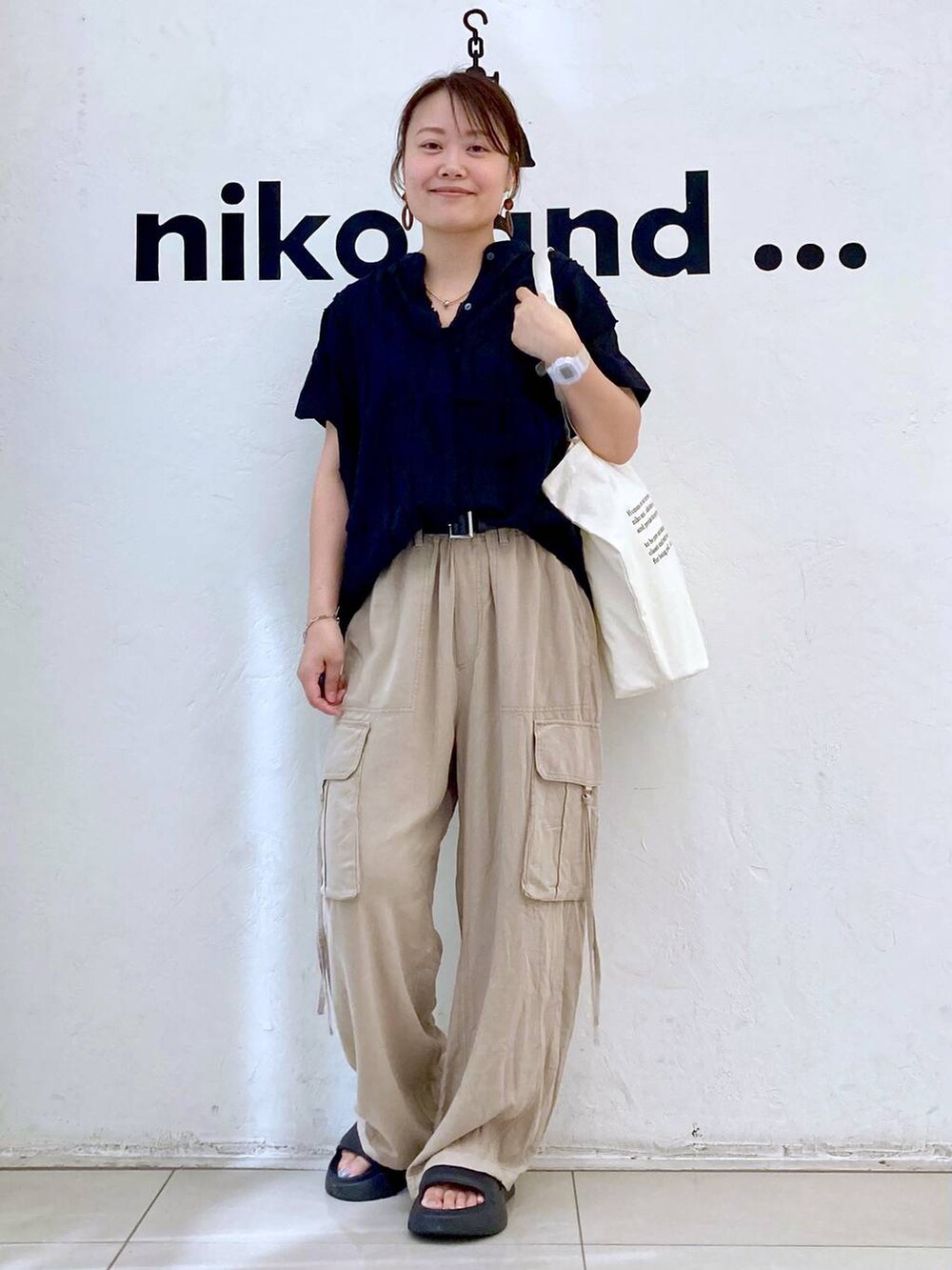 ブラック系のサンダル、ベージュ系のカーゴパンツ、ベージュ系のトートバッグを着用したレディースの夏コーディネートの2枚目の写真