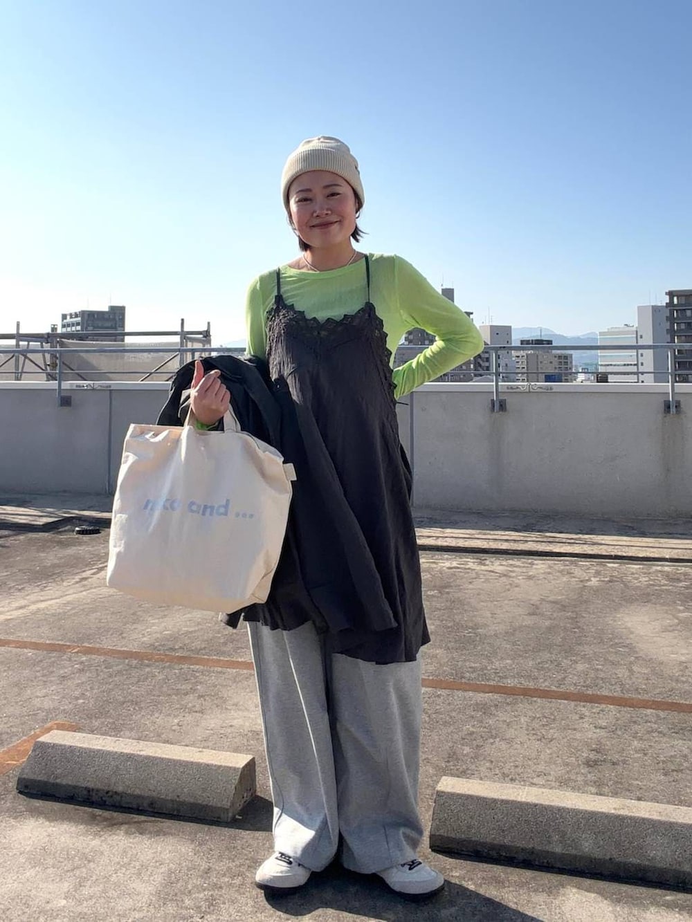 ホワイト系のトートバッグ、ブラック系のブルゾン、グレー系のワンピースを着用したレディースの冬コーディネートの4枚目の写真