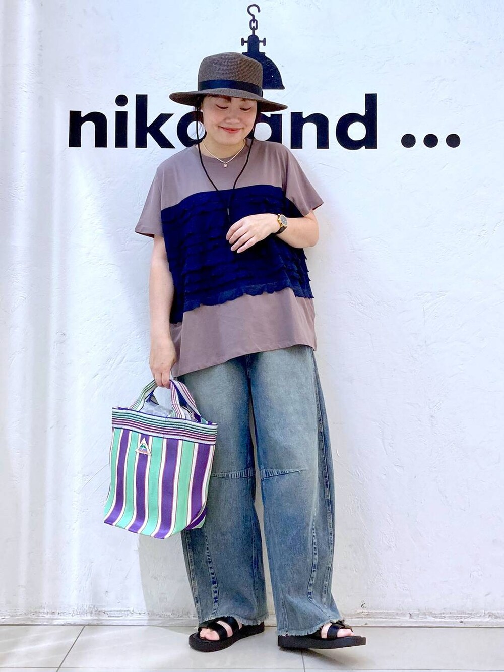 ブルー系のその他パンツ、グリーン系のトートバッグ、ブラウン系のTシャツ/カットソーを着用したレディースの夏コーディネートの2枚目の写真