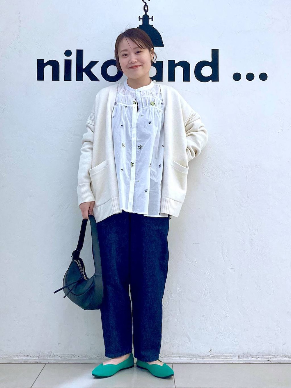 ブラック系のショルダーバッグ、ホワイト系のシャツ/ブラウス、グリーン系のパンプスを着用したレディースの春コーディネートの2枚目の写真