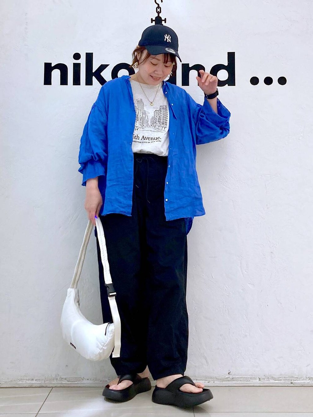 ブラック系のサンダル、ベージュ系のTシャツ/カットソー、ホワイト系のショルダーバッグを着用したレディースの春コーディネートの2枚目の写真