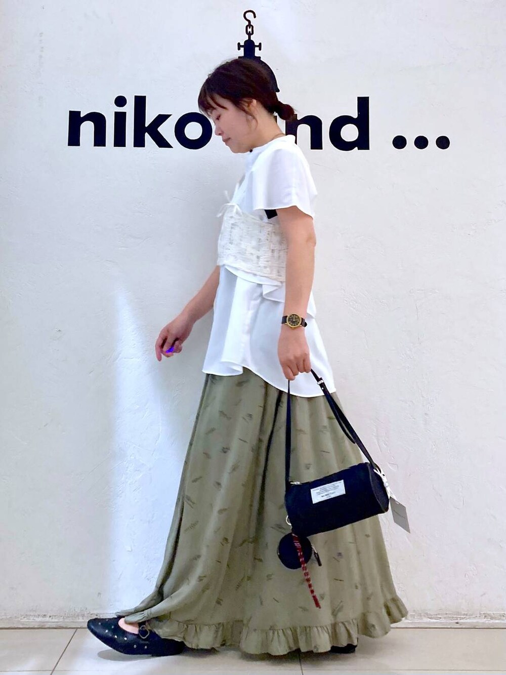 ブラック系のパンプス、ブラック系のショルダーバッグ、グリーン系のスカートを着用したレディースの夏コーディネートの3枚目の写真