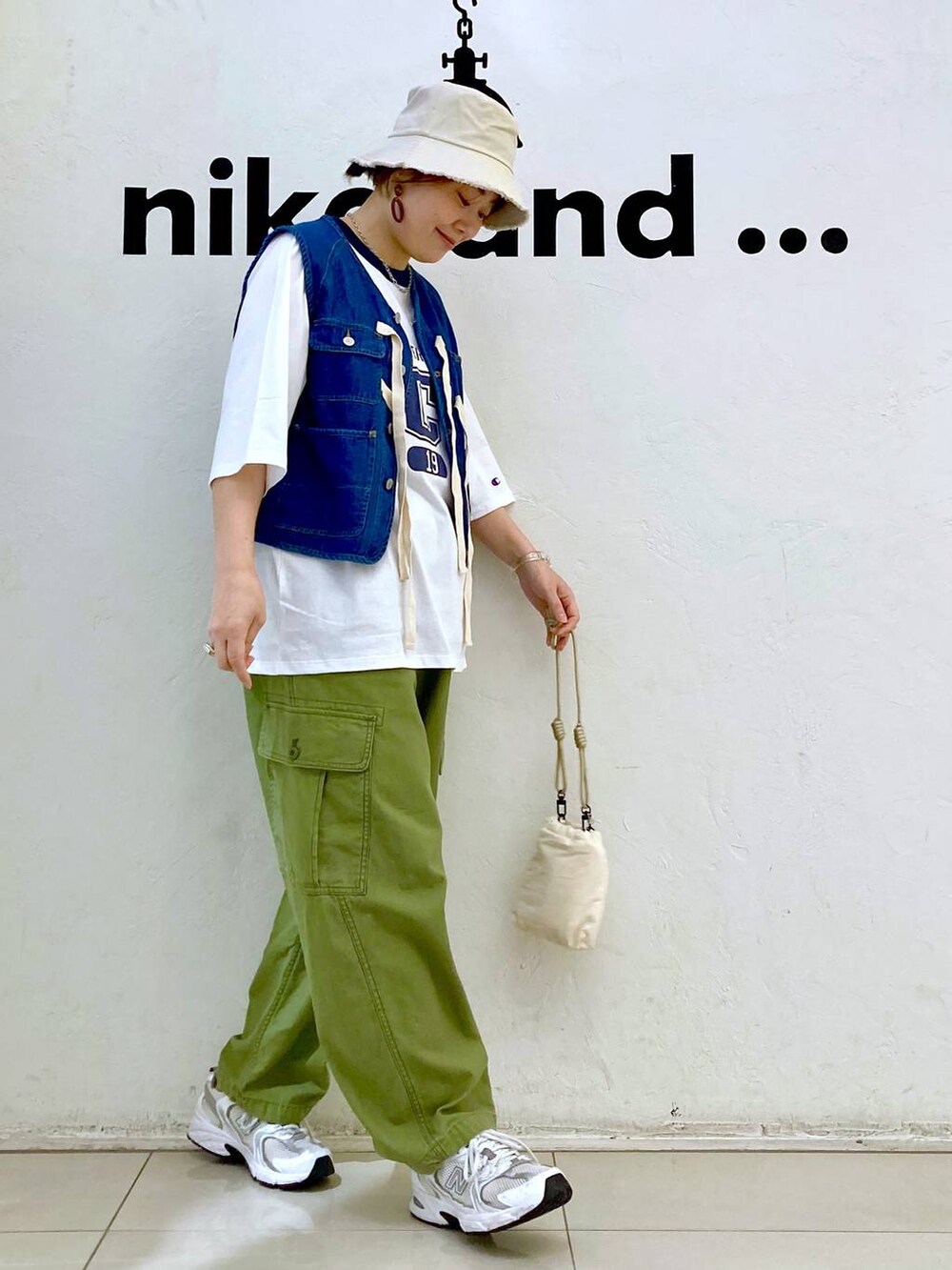 ブルー系のベスト、ベージュ系のショルダーバッグ、グリーン系のカーゴパンツを着用したレディースの春コーディネートの3枚目の写真