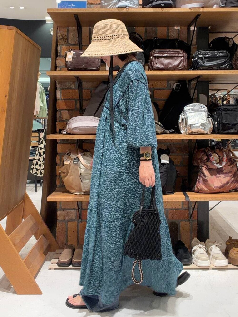 ブルー系のデニムパンツ、ブルー系のワンピース、ブラック系のトートバッグを着用したレディースの春コーディネートの4枚目の写真