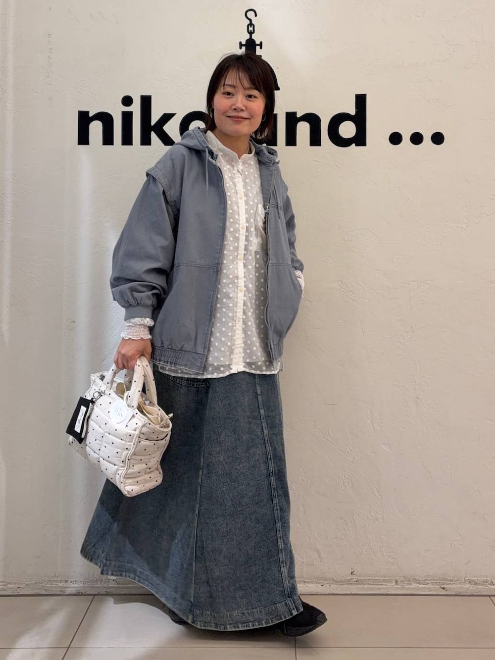 ブルー系のスカート、ホワイト系のトートバッグ、ブルー系のブルゾンを着用したレディースの冬コーディネートの2枚目の写真