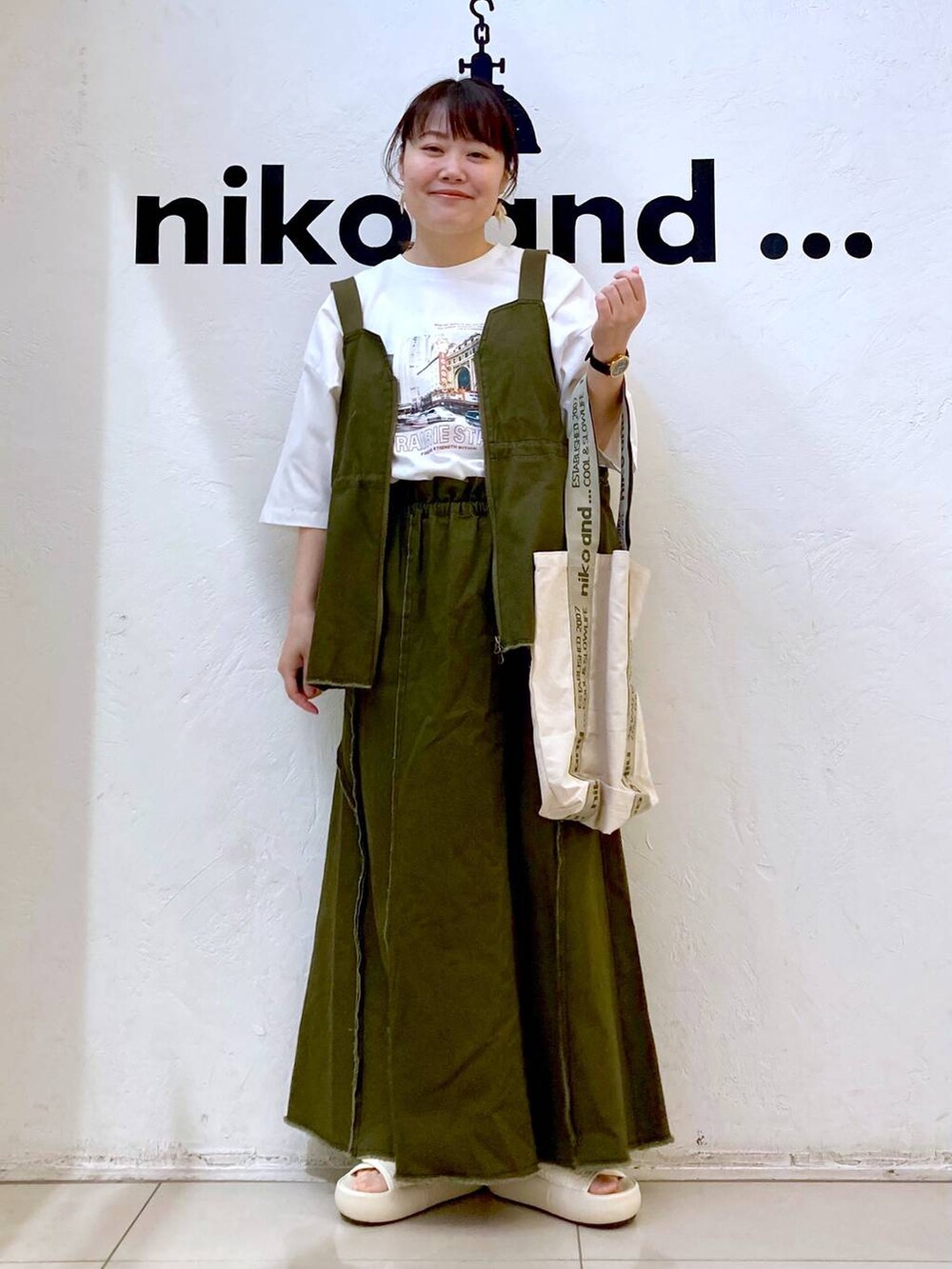 ベージュ系のトートバッグ、ベージュ系のサンダル、ホワイト系のTシャツ/カットソーを着用したレディースの春コーディネートの2枚目の写真