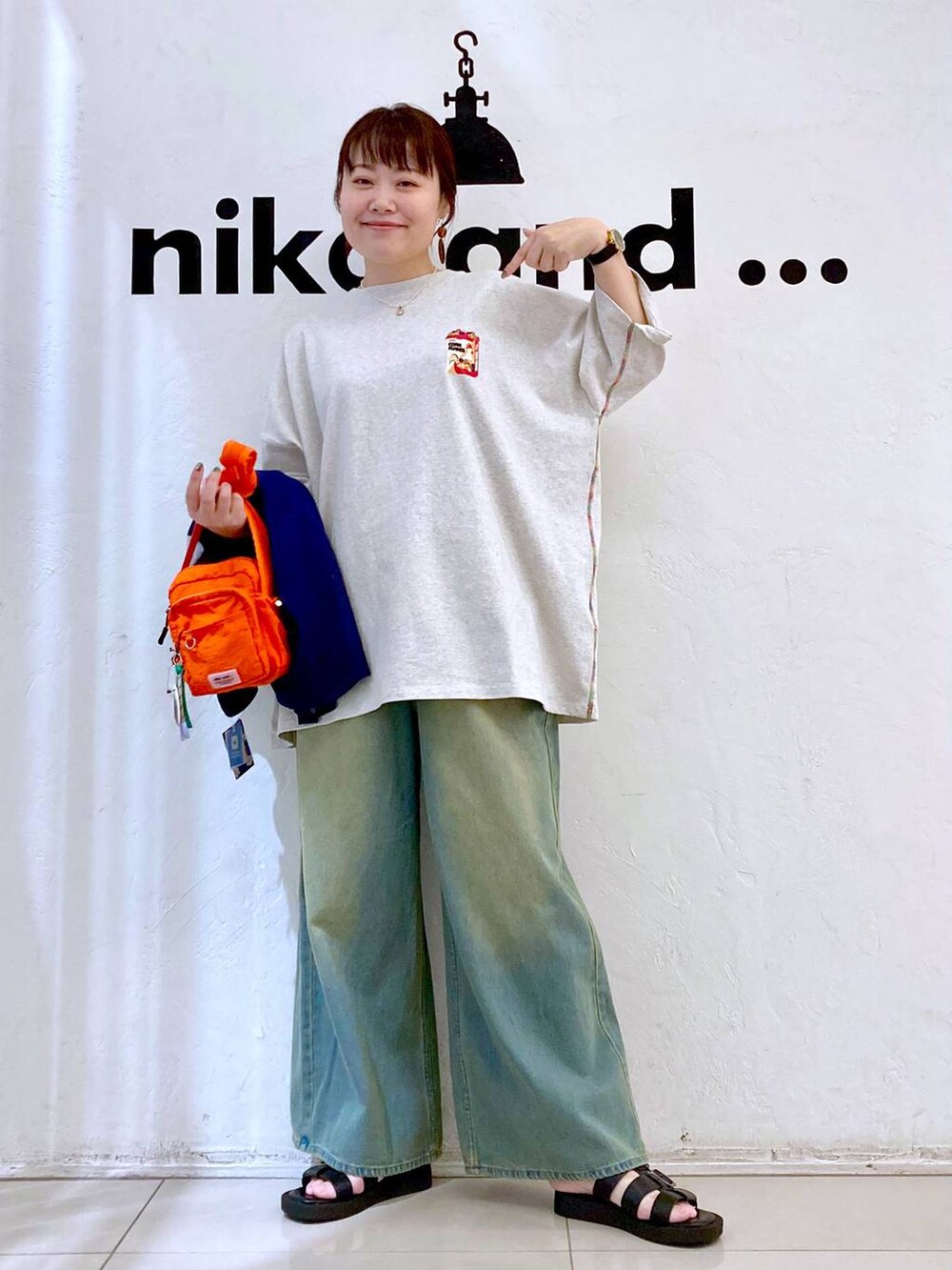 オレンジ系のショルダーバッグ、ベージュ系のTシャツ/カットソー、ブルー系のデニムパンツを着用したレディースの夏コーディネートの2枚目の写真