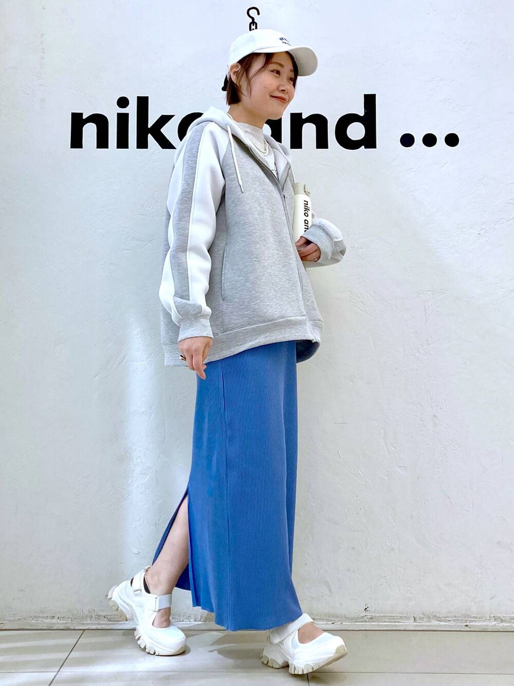 ベージュ系のTシャツ/カットソー、ベージュ系のスニーカー、ブルー系のスカートを着用したレディースの冬コーディネートの5枚目の写真