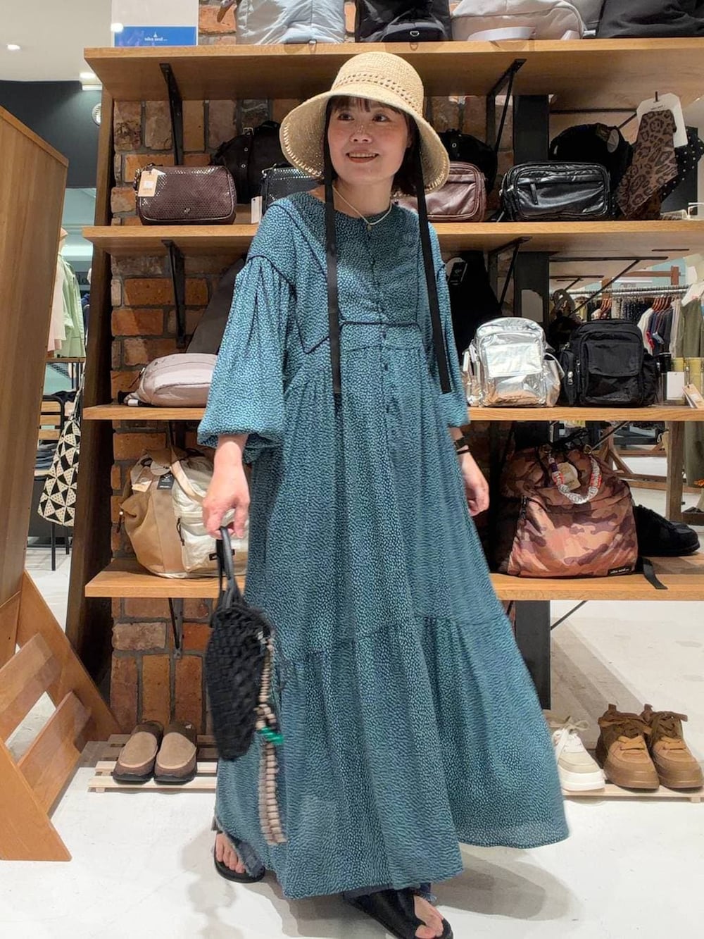 ブルー系のデニムパンツ、ブルー系のワンピース、ブラック系のトートバッグを着用したレディースの春コーディネートの3枚目の写真
