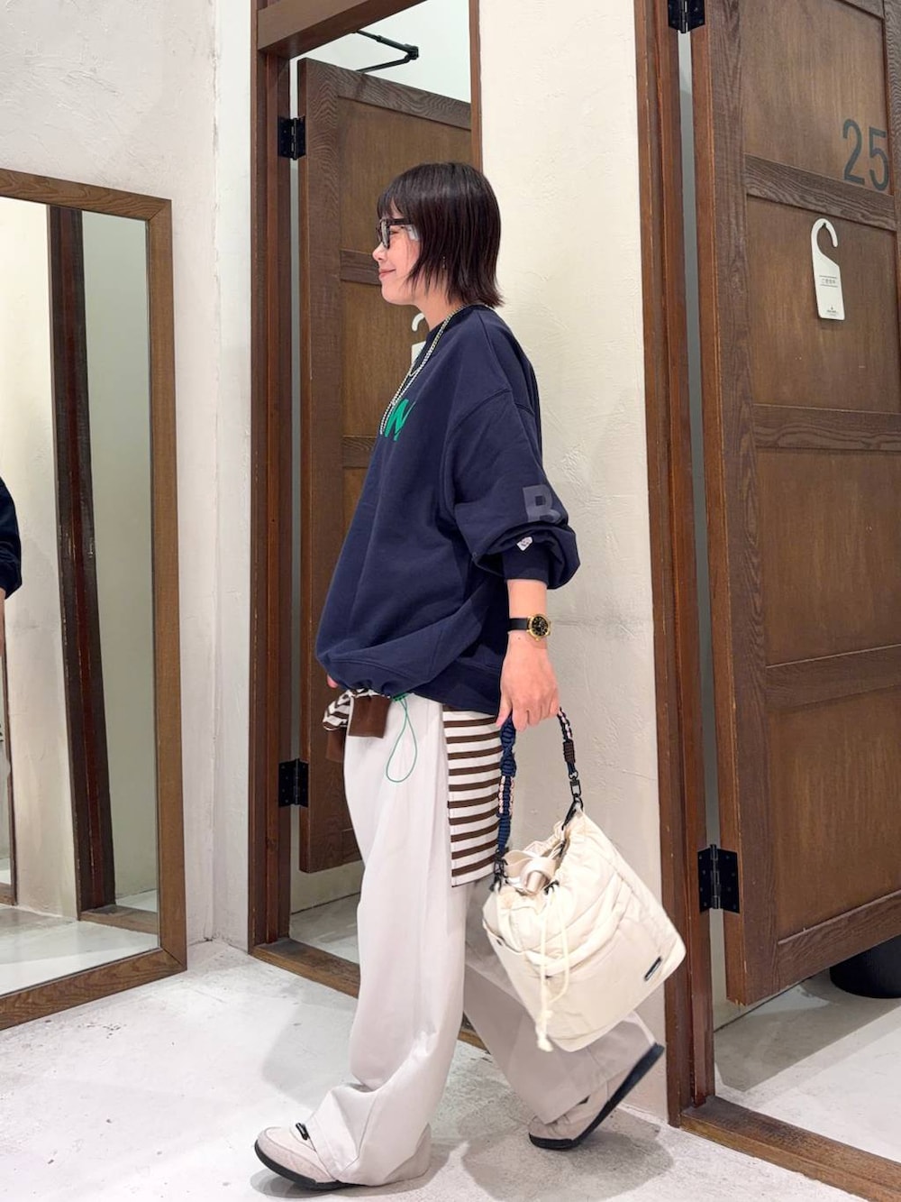 ベージュ系のチノパンツ、ベージュ系のショルダーバッグ、ブラウン系のサングラスを着用したレディースの冬コーディネートの5枚目の写真