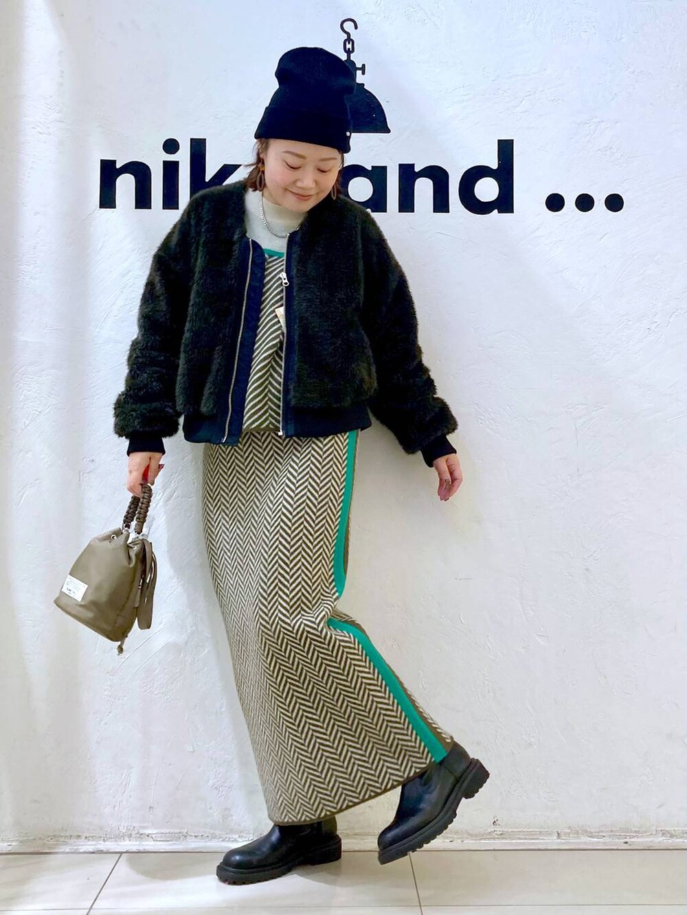 グレー系のブルゾン、グリーン系のショルダーバッグ、ブラウン系のスカートを着用したレディースの冬コーディネートの2枚目の写真