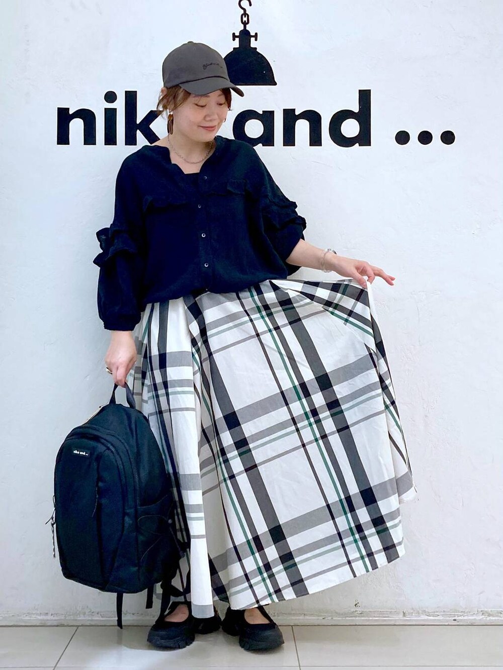 ブラック系のバックパック/リュック、ブラック系のシャツ/ブラウス、ベージュ系のスカートを着用したレディースの春コーディネートの2枚目の写真