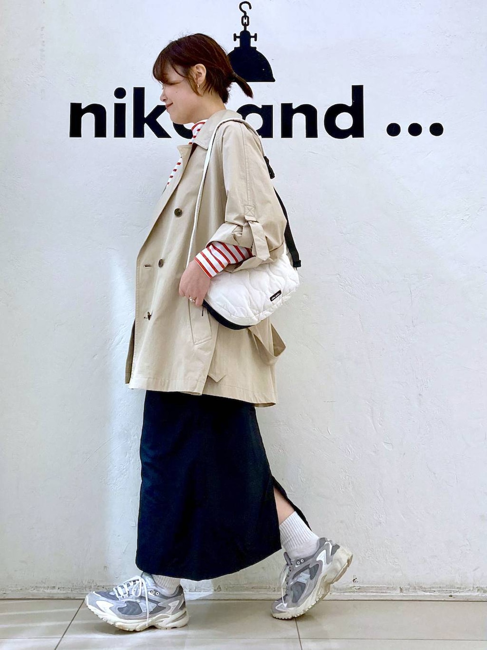 ベージュ系のトレンチコート、ベージュ系のショルダーバッグ、ブラック系のスカートを着用したレディースの春コーディネートの5枚目の写真