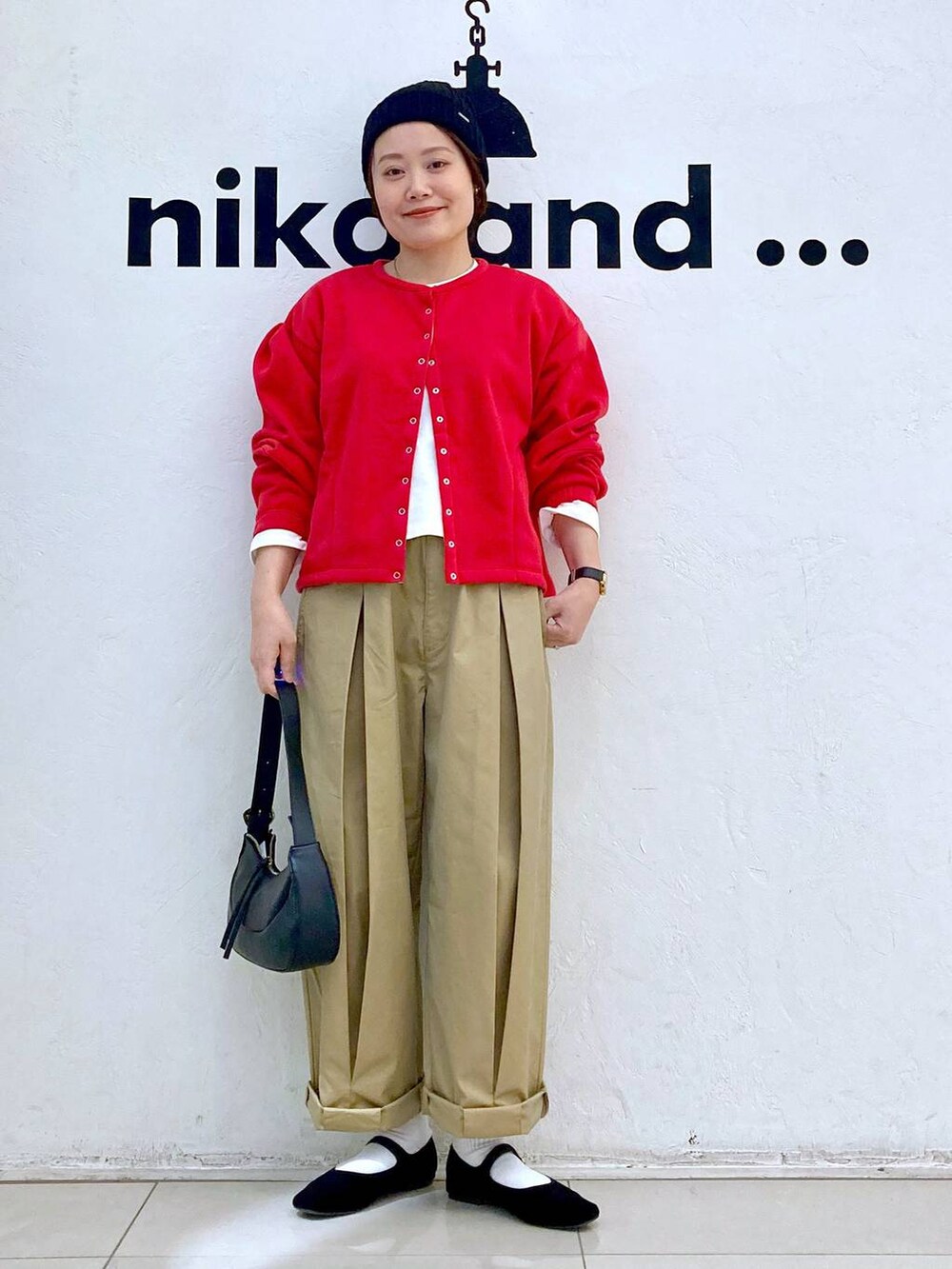 ブラック系のショルダーバッグ、ブラック系のパンプス、イエロー系のチノパンツを着用したレディースの冬コーディネートの5枚目の写真