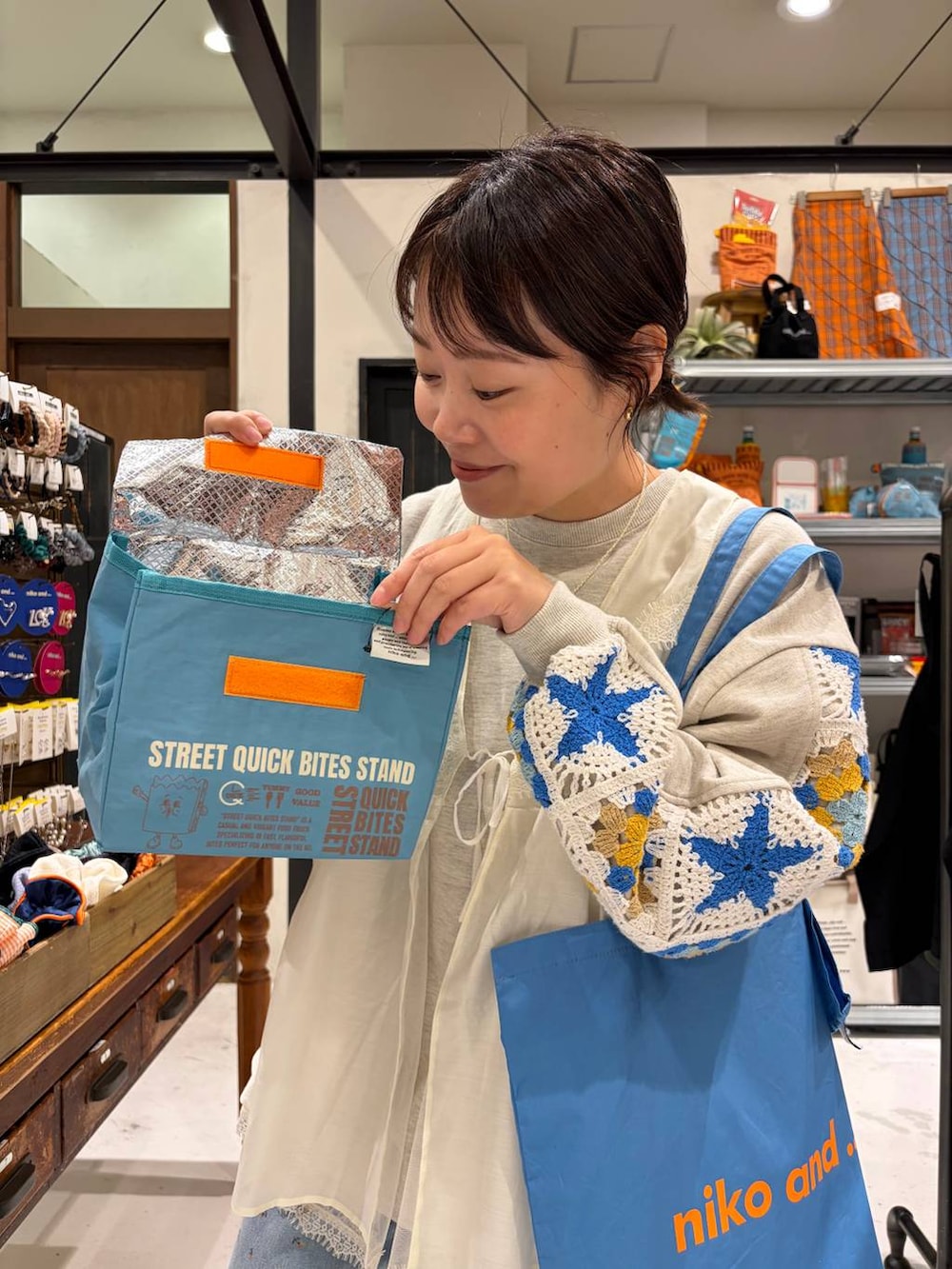 ベージュ系のスウェット、ブルー系のトートバッグ、ブルー系のデニムパンツを着用したレディースの春コーディネートの6枚目の写真